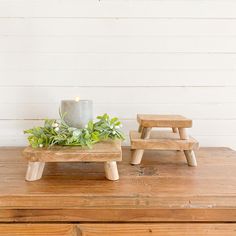 two wooden stools sitting on top of a wooden table next to a potted plant