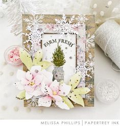 a close up of a card with flowers and snowflakes on the table next to yarn