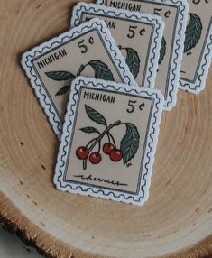 four michigan stamps with cherries on them sitting on top of a piece of wood