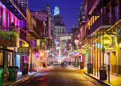 an empty city street at night with neon lights on the buildings and signs lit up