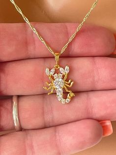 This stunning gold filled scorpion pendant necklace.   This 14kt gold filled CZ Scorpion charm measures 21x16mm, has a 6mm bail and hangs on a 14kt gold filled shiny Singapore chain chain with spring clasp closure.  Comes nicely boxed, the perfect present. Model is wearing 18" length. Available in 18 inch or 20 inch length. If you choose 20 inch length you'll receive an 18 to 20 inch adjustable chain. Why you should choose Gold Filled Jewelry... Gold filled jewelry is an actual layer of gold pre Gold Scorpion, Cz Scorpion, Scorpion Necklace, Necklace Women Gold, Scorpio Necklace, Zodiac Astrology, Necklace Women, Book Decor, Gold Filled Jewelry