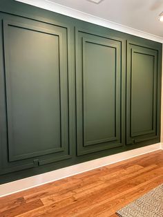 an empty room with green cabinetry and wood flooring in the center, along with a rug on the floor