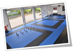 an indoor gym with blue mats and windows