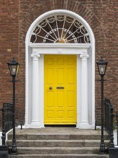 a bright yellow door sits in front of a brick building