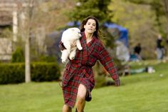 a woman in a red and black plaid dress holding a white dog on her back