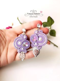 DESCRIPTION: Soutache earrings, lilac earrings dangle Made with - Soutache Gold - Rivoli 12 mm - Pearls Swarovski Elements!  - Silver metal pearls 3 mm - Rocailless Miyuki 15/0 and 11/0 - Rhinestone chain - Hypoallergenic steel components - Alcantara All my jewels are made of Soutache, beads and crystals, high quality components. All jewels are handmade Designed and created by Vanessa Sabstier! CUSTOM: The VSBJewelryDesigner shop also produces commissioned accessories. To see all the items on sale visit my Etsy shop. For special requests or customizations contact me in private! Lilac Earrings, Arm Accessories, Orange Earrings, Rhinestone Chain, Soutache Earrings, Soutache Jewelry, Red Earrings, Green Earrings, Blue Earrings