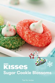 two sugar cookie blossoms on a white plate with green and red sprinkles