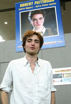 a young man standing in front of a poster with robert pattiinson on it