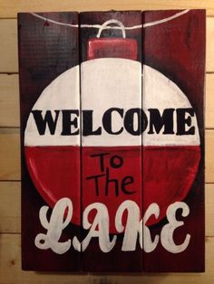 a wooden sign that says welcome to the lake with a red and white ball on it