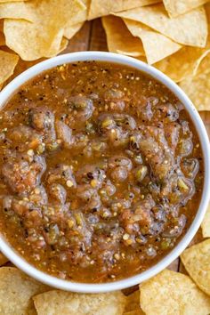 a white bowl filled with salsa surrounded by tortilla chips