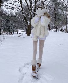 a woman is standing in the snow with her feet up wearing boots and a fur coat