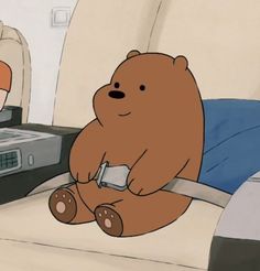 a cartoon bear sitting on top of a bed next to a remote control