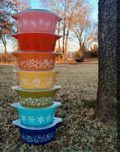 a stack of colorful bowls sitting next to a tree