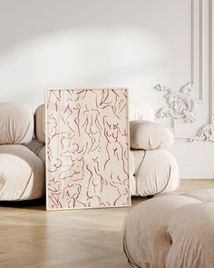 an abstract painting is on the floor in front of a couch and footstool