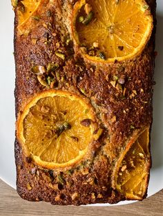 slices of bread with oranges and pistachio on top sitting on a white plate