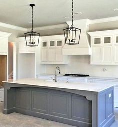 a large kitchen with white cabinets and gray island counter tops, two pendant lights over the sink