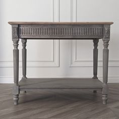 a wooden table sitting on top of a hard wood floor next to a white wall