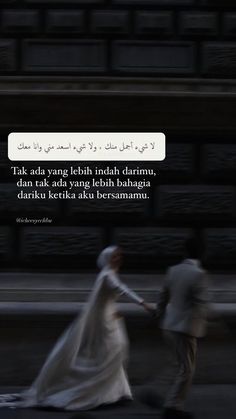 a man and woman are walking down the street in front of a building with an arabic quote on it