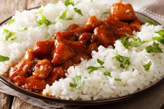 a plate filled with rice and meat covered in gravy on top of a wooden table