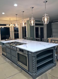 a large kitchen with an island in the middle and two lights hanging from the ceiling