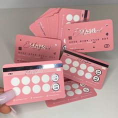 several pink cards with white polka dots are being held by a person's hand