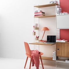 a desk with a chair, lamp and bookshelf