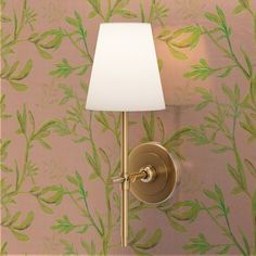 a wall lamp with a white shade on it in front of a floral wallpaper