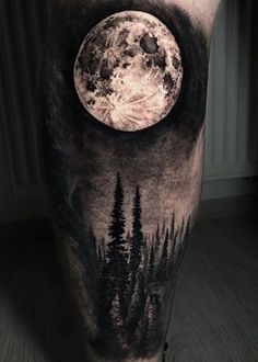 a man's leg with a full moon and trees on it