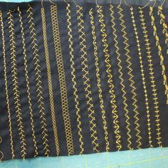 a piece of black fabric with yellow thread on it and some scissors next to it