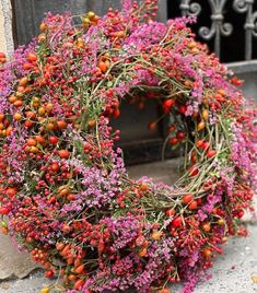 a wreath made out of flowers sitting on the ground next to a building with an iron gate