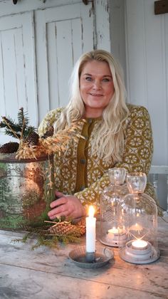 a woman sitting at a table with some candles in front of her and other decorations on the table