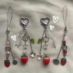 four charms are attached to each other on a white sheet with hearts and strawberrys