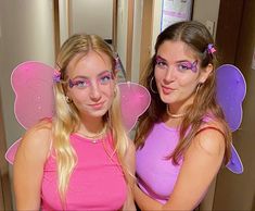 two girls dressed in pink and purple posing for the camera with their faces painted like fairy wings