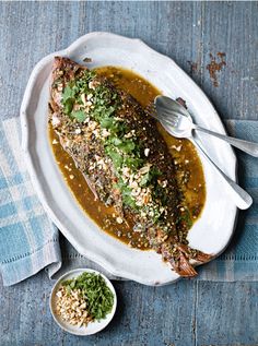 a white plate topped with fish covered in gravy and garnishes