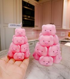 two small pink pigs sitting on top of a counter next to a person's hand