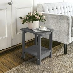 a small table with a potted plant on it next to a couch and door