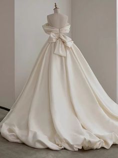 a white wedding dress with a bow on the back