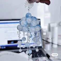 a person is holding some glass beads in front of a laptop computer on a desk