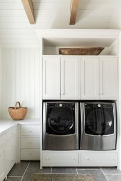 a washer and dryer in a white laundry room with built - in cabinets