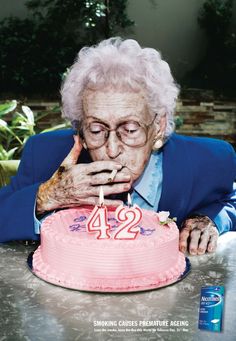 an old woman blowing out the candles on her birthday cake