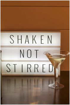 a martini glass sitting on top of a table next to a sign that says shaken not stirred