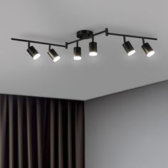 a ceiling light with five lights in the middle of it and curtains on the other side