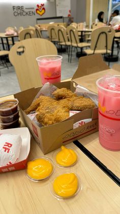 some food and drinks on a table at a fast food restaurant with people in the background