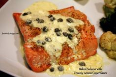 salmon with creamy lemon caper sauce and broccoli on a white platter