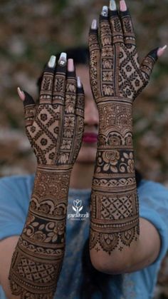 a woman holding her hands up with henna tattoos on it's arms and hand