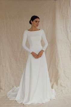 a woman wearing a white wedding dress with long sleeves