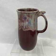 a brown and white mug sitting on top of a glass stand