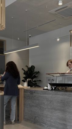 a woman standing in front of a counter next to a person sitting at a desk