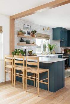 a kitchen with blue cabinets and white counter tops, wooden flooring and open shelving