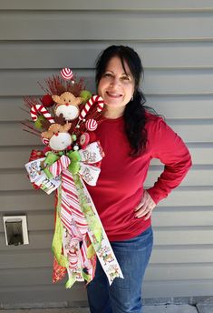 a woman standing next to a wall holding a bouquet of candy canes and candies